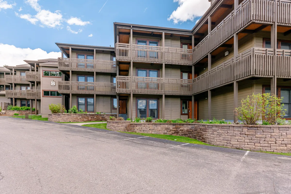 A wider exterior shot captures the property’s balconies, landscaped garden area, and entrance doors. The image suggests both private and social outdoor spaces, ideal for casual gatherings or starting an evening out.