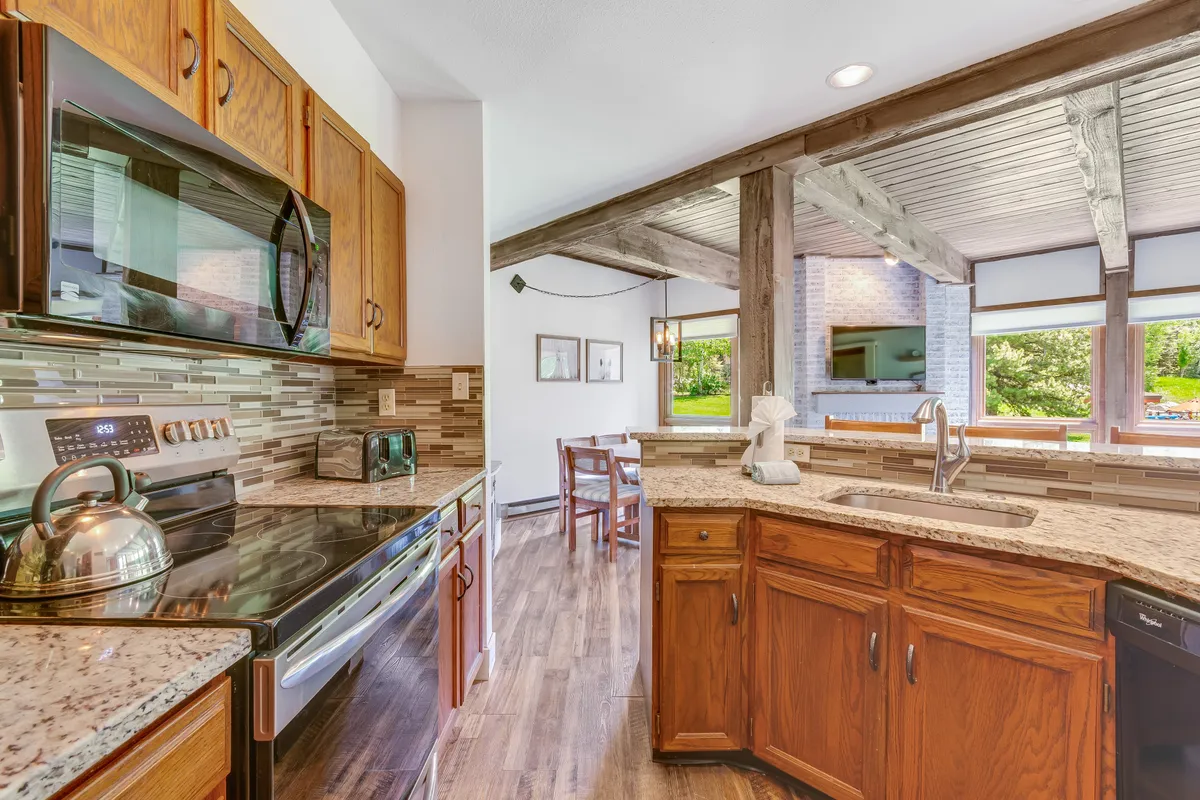 The kitchen is showcased here with a spacious island, stainless steel appliances, granite countertops, and a dining area illuminated by natural light. The space is inviting for cooking, entertaining, and enjoying family meals.