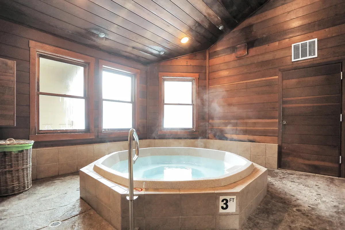 This interior shot focuses on an indoor hot tub, framed by wood paneling and windows that let in natural light. The space is designed for relaxation and rejuvenation, echoing the resort's spa-like amenities.