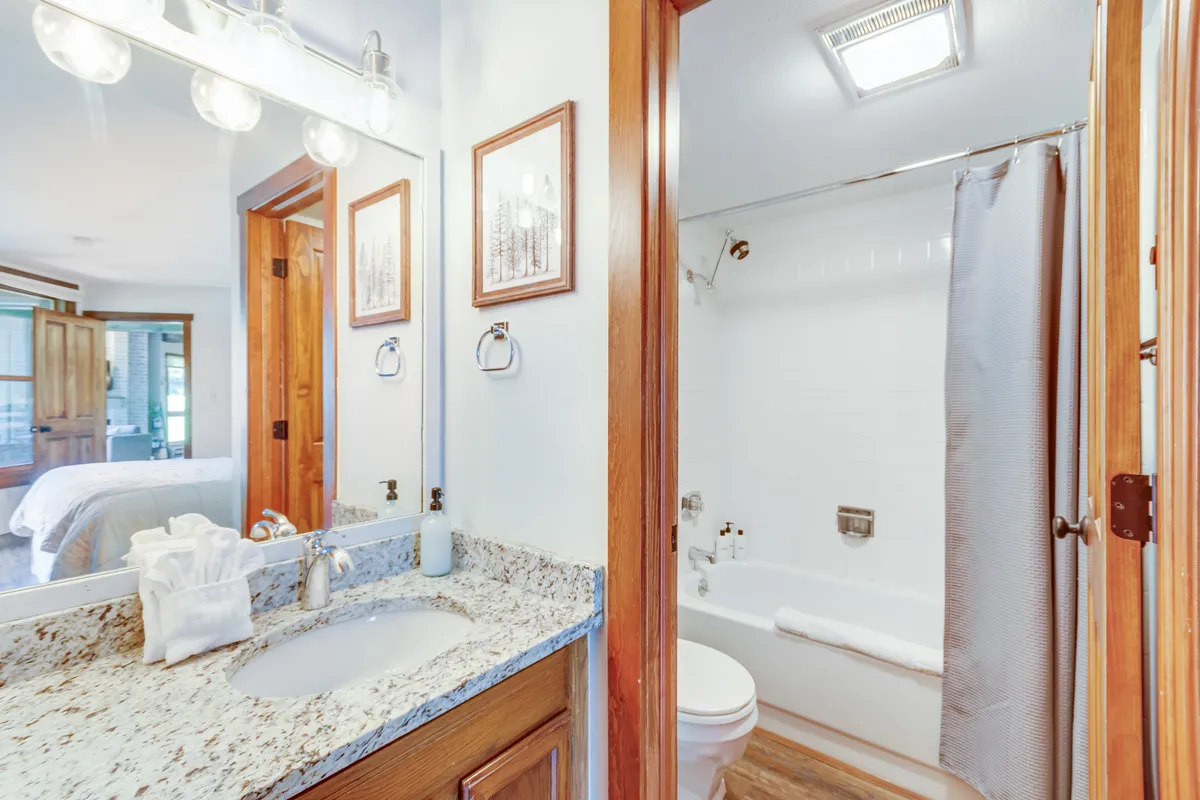 A bright bathroom featuring a granite countertop, modern fixtures, framed artwork, and a bathtub—perfect for relaxing soaks or quick refreshes. The design is both functional and soothing, echoing the retreat's emphasis on rejuvenation.